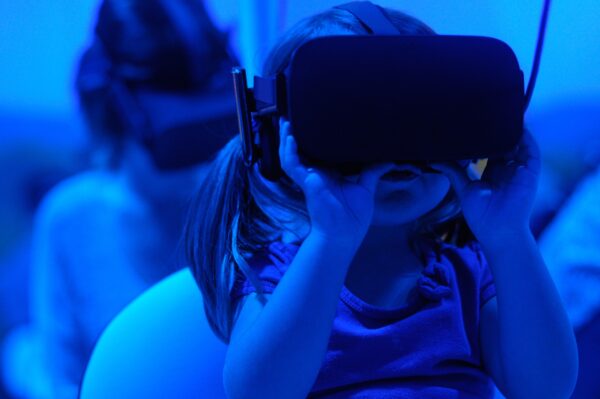A child looks through a VR headset. The image is tinted blue.