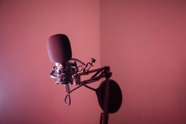 A microphone on a swing arm with a pink wall for a background.