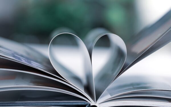 A book is open on a desk so the pages fold in to form a heart.